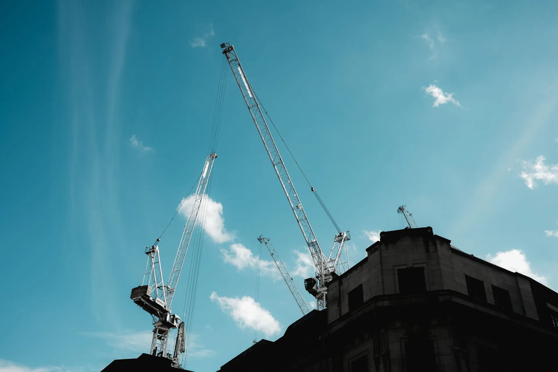 Silhouetted construction cranes extend into a clear blue sky, illustrating Vertical SaaS