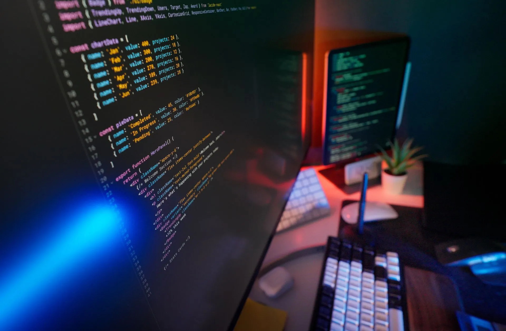 A vibrant workspace featuring colorful code on computer monitors, ideal for developers, illustrating Vulnerability disclosures doubled to 10,740 a month, Google says, as AI reshapes