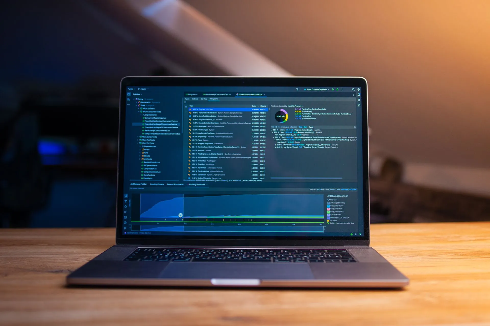 A laptop displaying code on a wooden desk, in a dimly lit workspace, illustrating Windows 11 2026 Update is out, and many of its features already came in monthly updates
