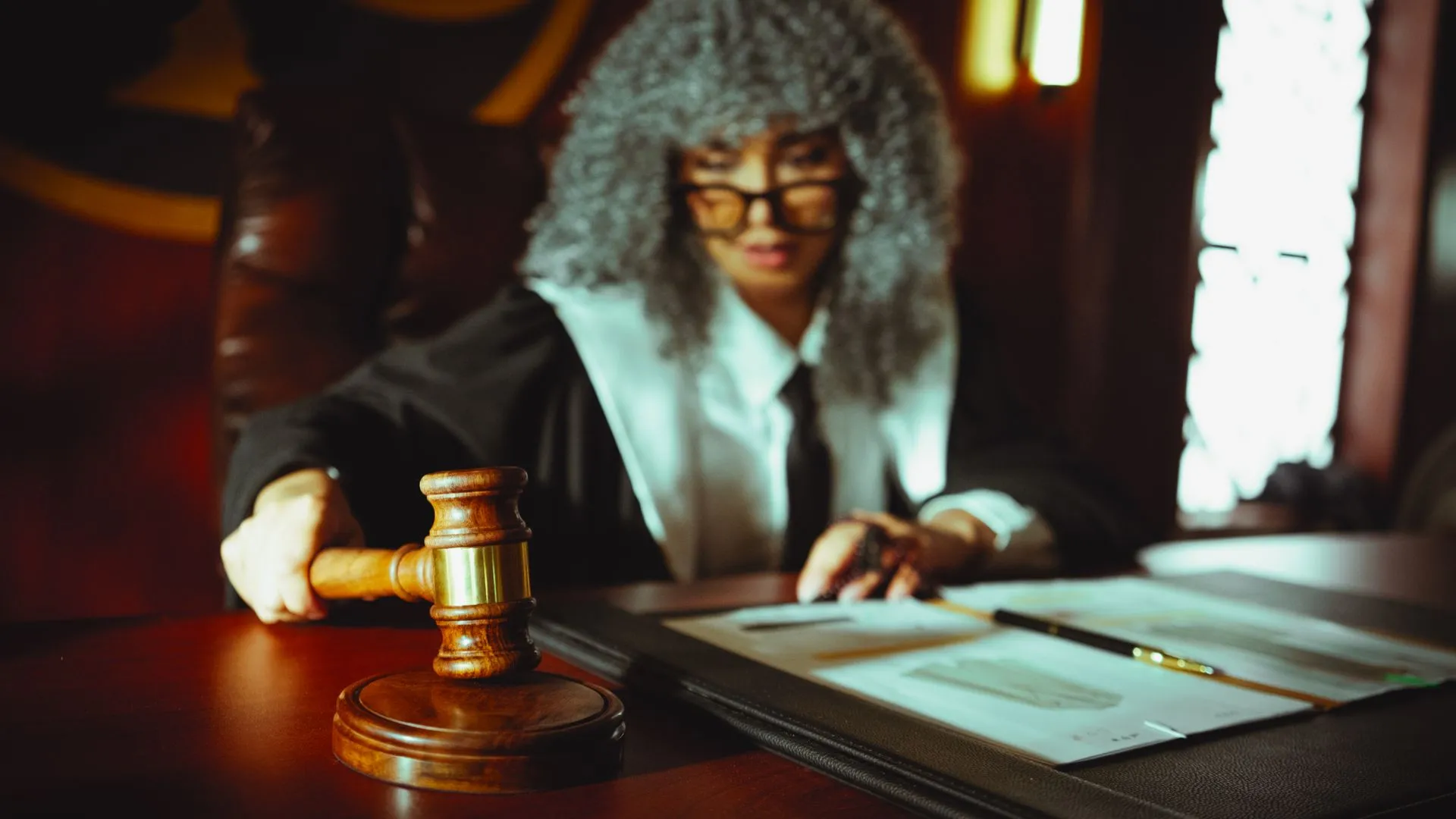 Female judge in a courtroom setting, focusing on legal documents with a gavel, illustrating Zoe Financial agrees to $450,000 SEC penalty over undisclosed adviser referral conflict