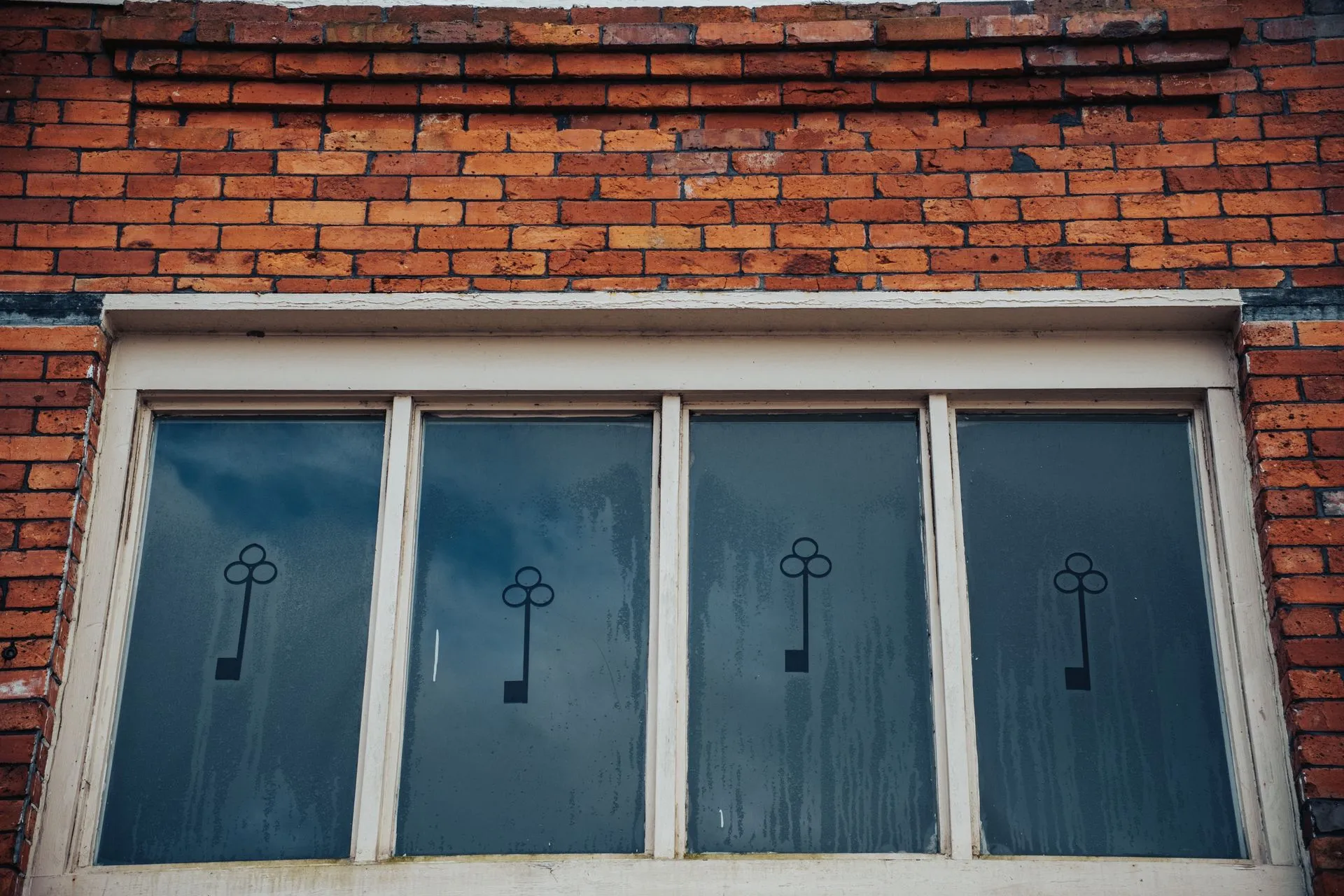 Close-up of a vintage brick wall with decorative frosted glass windows and key motif, illustrating AppFolio Realm-X takes on multi-step work as AI startup EliseAI hits $4 billion