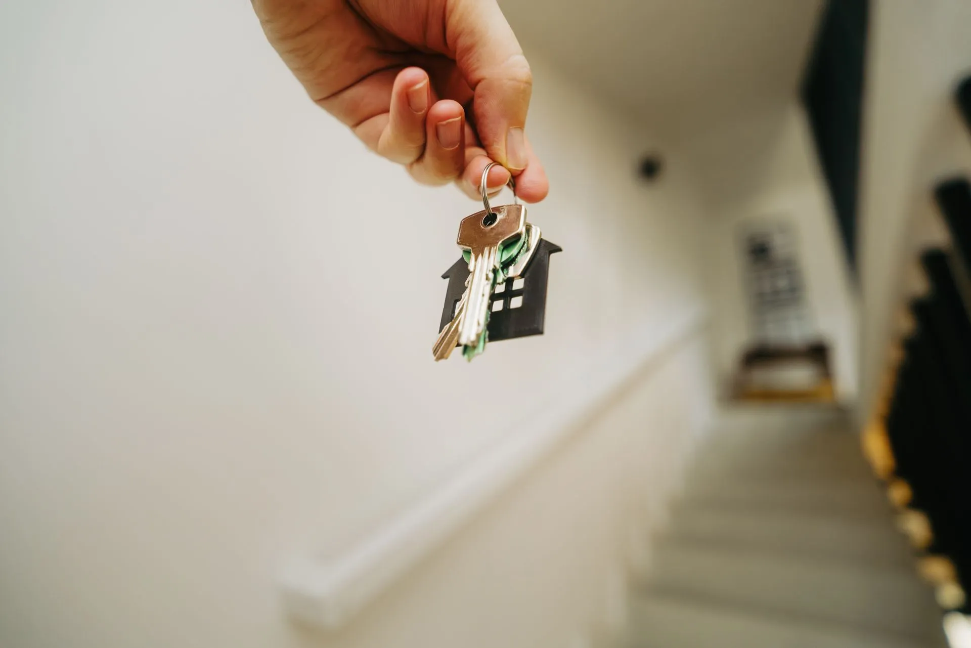 Close-up of a hand holding a keychain in the shape of a house, symbolizing real estate and property ownership, illustrating EliseAI funding