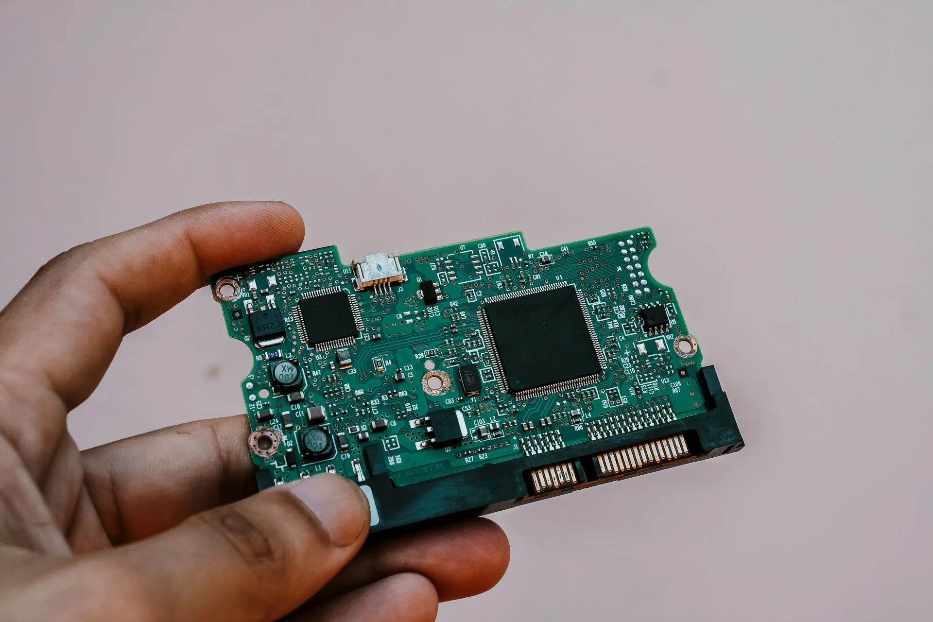 Close-up image of a hand holding a circuit board from a hard drive, showcasing electronic technology, illustrating Google's Gemini 4 Argon goes to vetted cyber defenders first, without