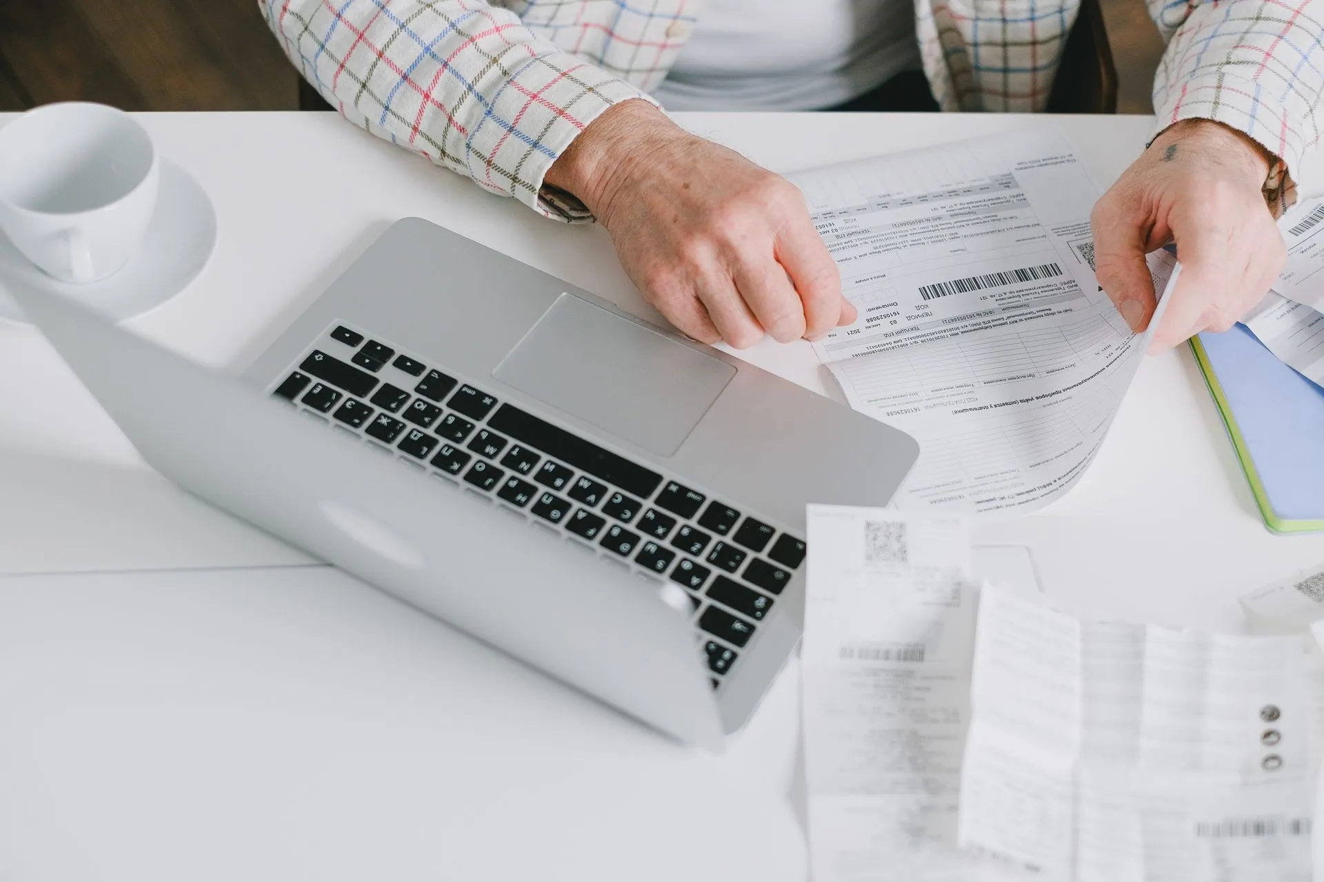Close-up of hands organizing documents on a desk with a laptop, illustrating Salesforce Flex Credits will meter AI agent API calls, with the rate still TBA